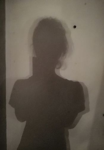 Rear view of silhouette woman standing against wall