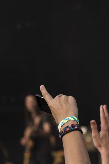 Cropped hand of man wearing bracelet holding smart phone outdoors