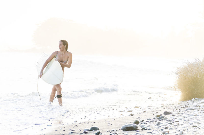 Woman with surfboard walking at beach