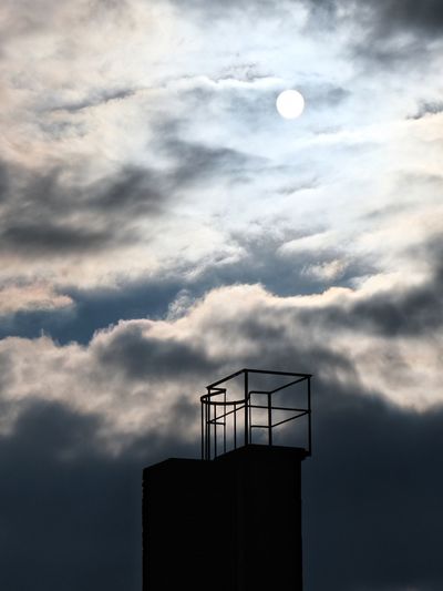 Low angle view of silhouette factory against sky at sunset