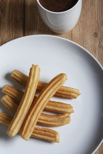 Churros with chocolate on wooden background. isolated and vertical image