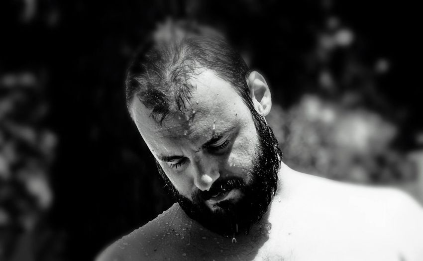 Close-up of wet shirtless bearded man standing outdoors on sunny day