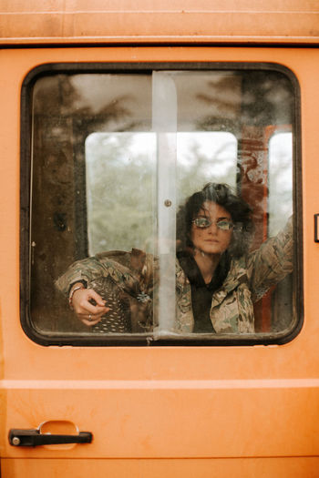 Portrait of woman sitting in bus seen through window