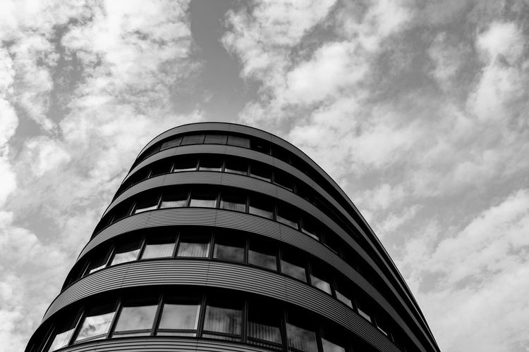 Low angle view of modern building against cloudy sky