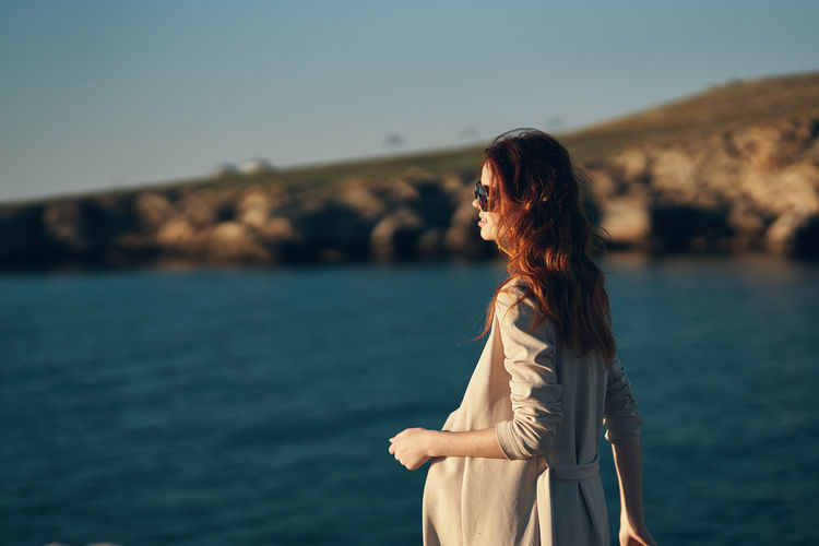 Woman standing near sea against sky