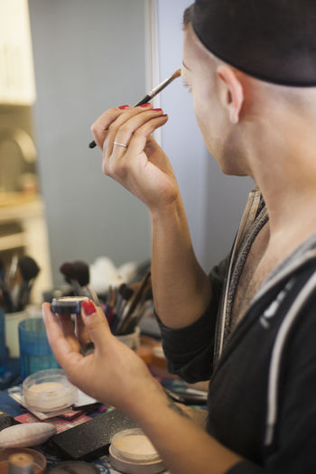 Young man applying drag makeup