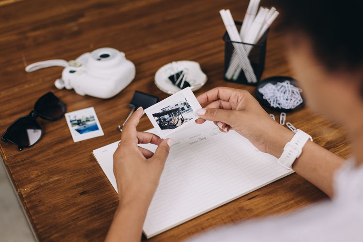 Over shoulder view of woman viewing a polaroid sitting at a table
