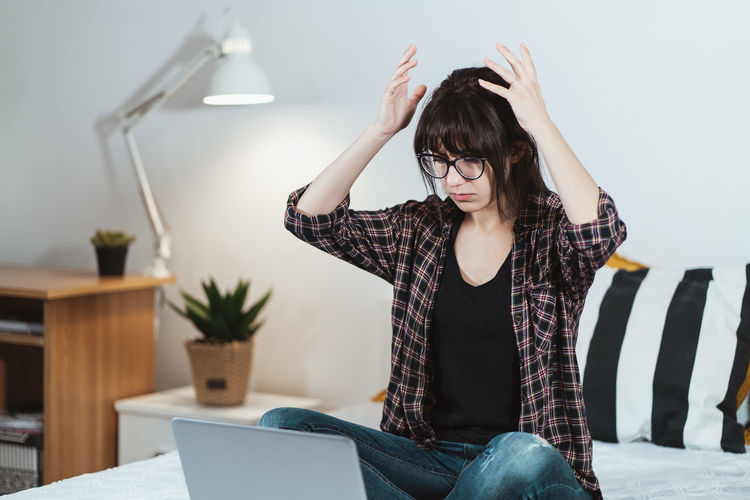 Frustrated young woman by laptop in office