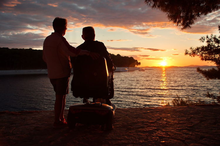 Senior couple standing on the adriatic seashore during sunset