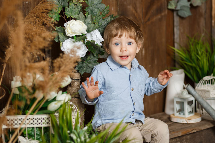 Portrait of cute boy smiling by flowering plants