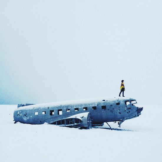 Full length of woman standing on abandoned airplane against sky during winter