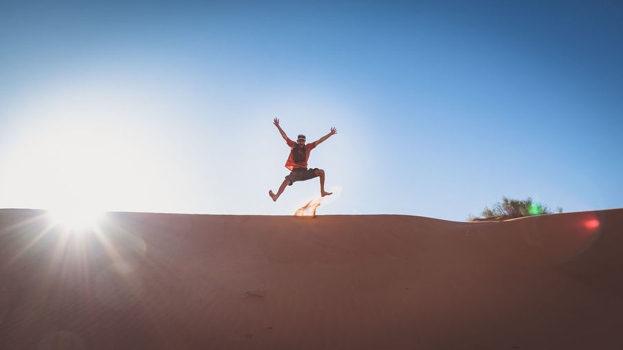 Low angle view of person jumping mid air in the desert