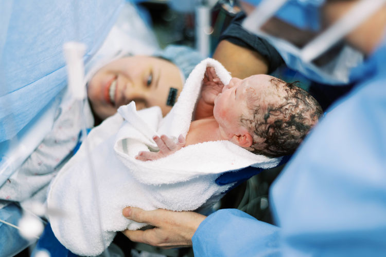 Little baby boy being born via cesarean section.