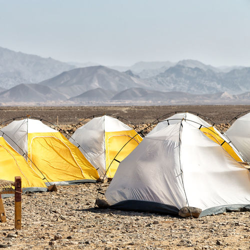 Tents on land against mountains and sky