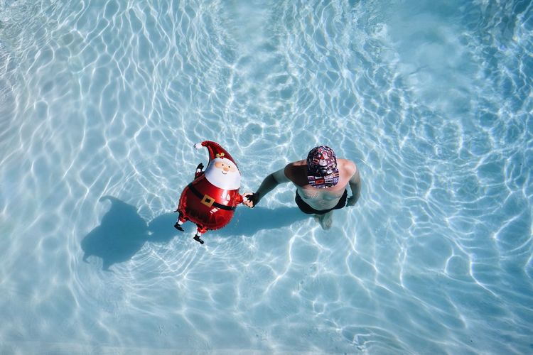 High angle view of man with santa claus balloon in swimming pool