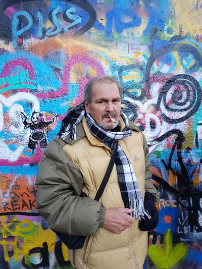 Full length of man standing against graffiti wall
