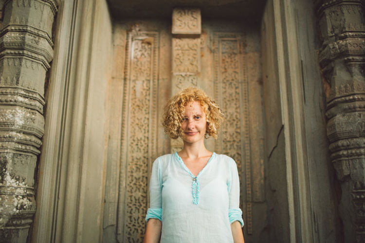 Portrait of smiling young woman standing at angkor wat