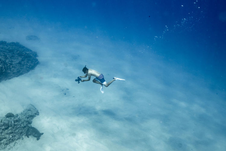Underwater photographer free diving to hawaii ocean floor