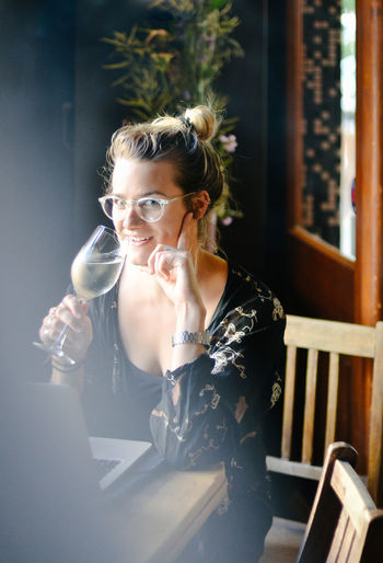 Portrait of woman drinking glass on table