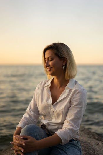 Portrait of middle aged woman standing at the beach at sunset
