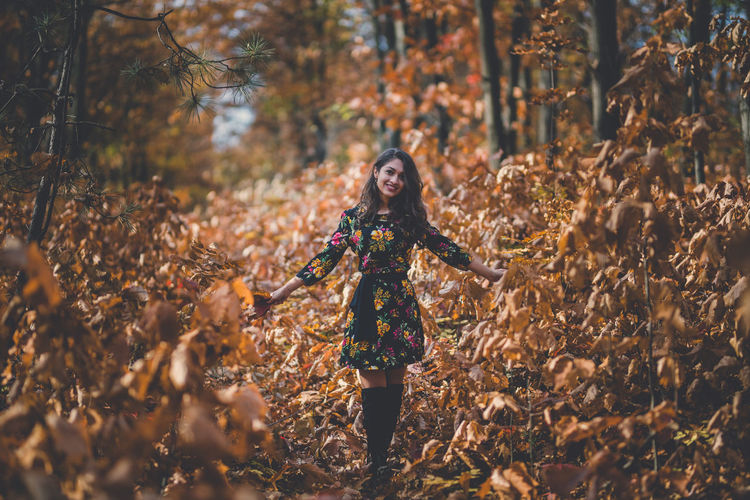 Portrait of young woman standing by plants in forest