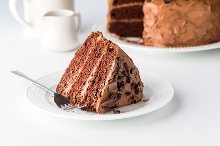 A large slice of triple layered decadent chocolate cake, ready for eating.