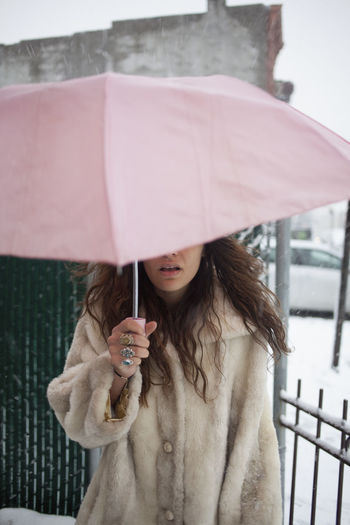Midsection of woman holding umbrella standing in winter