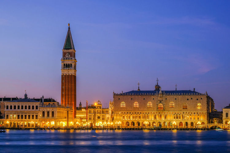 Low angle view of san marco campanile by river against sky at dusk