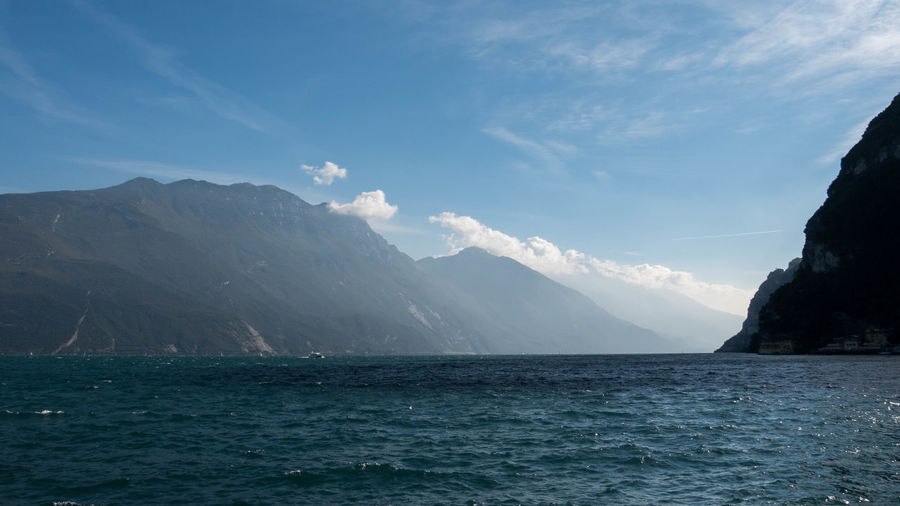 Scenic view of sea and mountains against cloudy sky