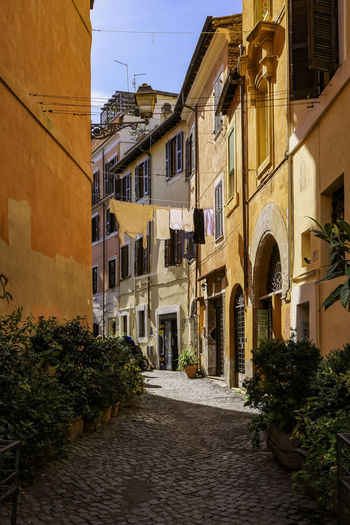 Picturesque small cobblestone alley in trastevere with tradional colorful houses - rome, italy