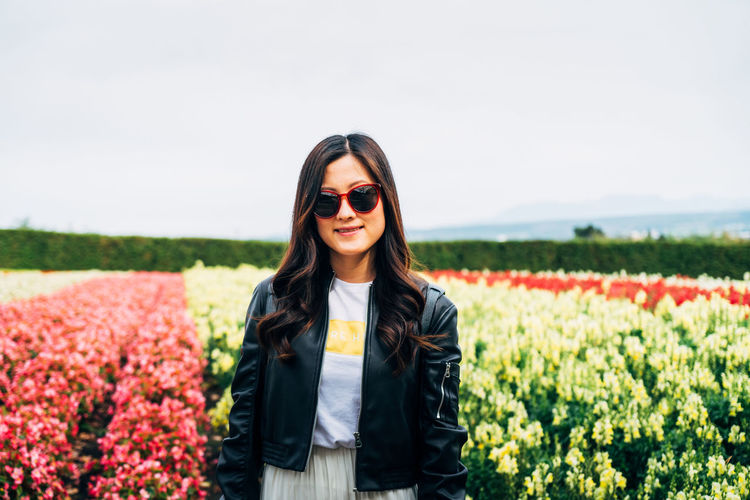 Portrait of smiling young woman standing against field