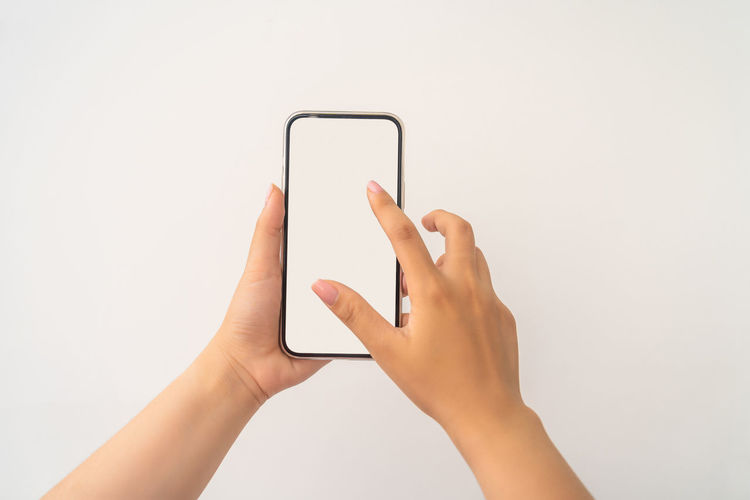 Midsection of person holding smart phone against white background
