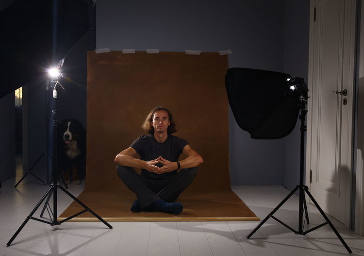 Portrait of man sitting on backdrop in studio