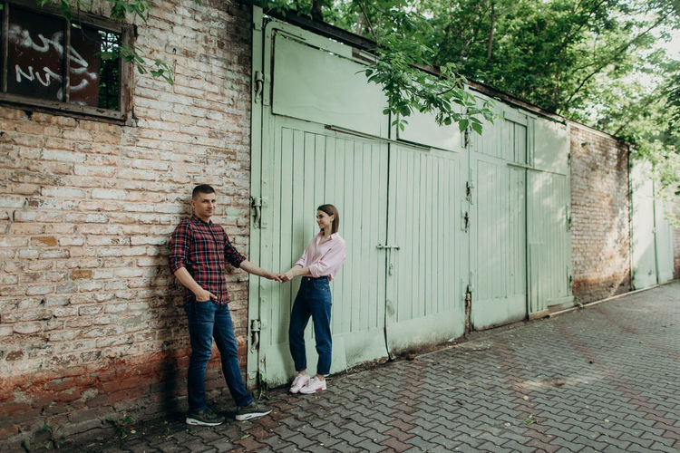 Couple holding hands while standing against wall