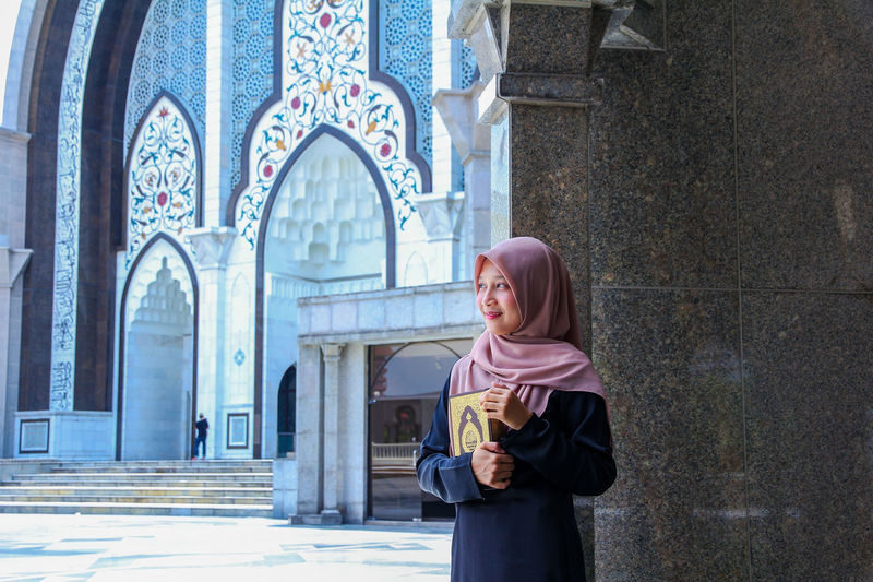 Woman holding holy book while standing in mosque