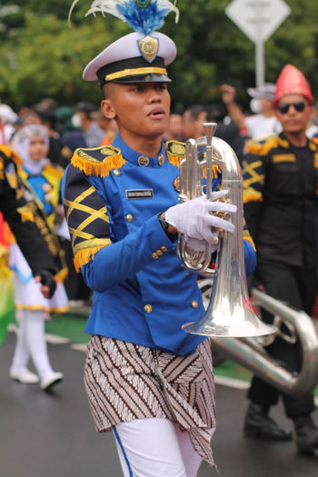 Other men play the trumpet in a marching band