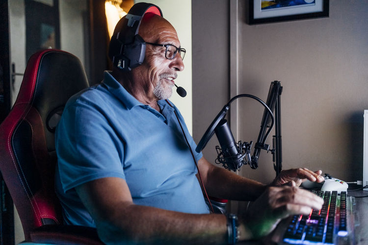 Senior man doing online streaming while playing video game at home