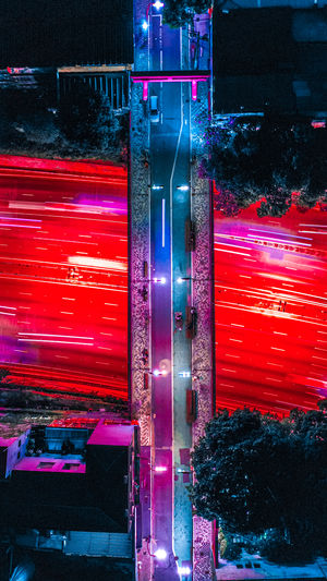 Aerial view of footbridge over illuminated light rails on road