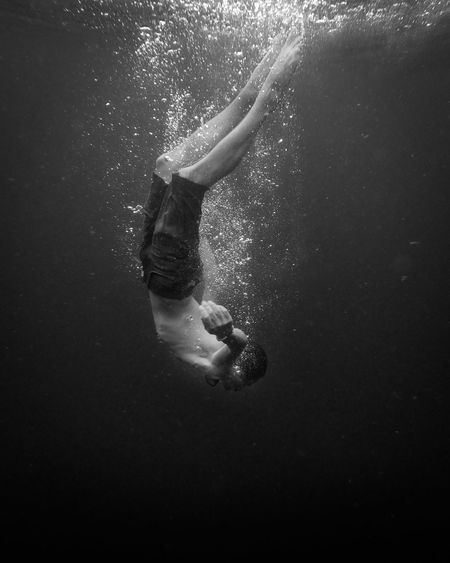 Man wearing short jeans swimming and floating in clear water