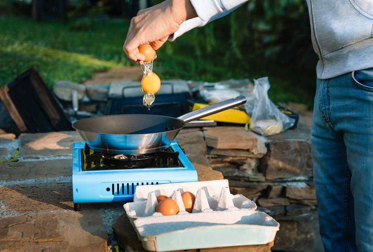 Midsection of man preparing food on camping stove