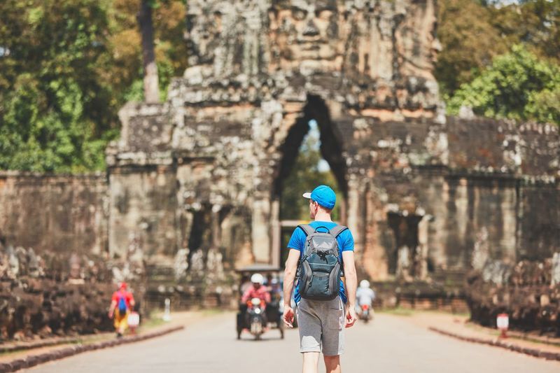 Rear view of young man with backpack walking towards built structure