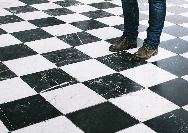 Low section of man standing on checked floor