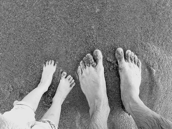 Low section of couple standing on sandy beach
