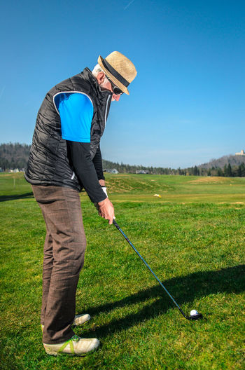 Full length of senior man playing golf against clear sky