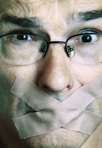 Close-up portrait of man with adhesive bandage on mouth