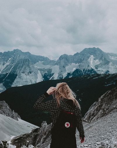 Woman standing on snowcapped mountain against sky