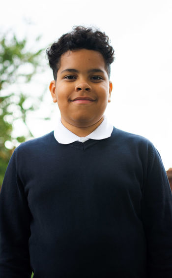 Portrait of young man standing against trees