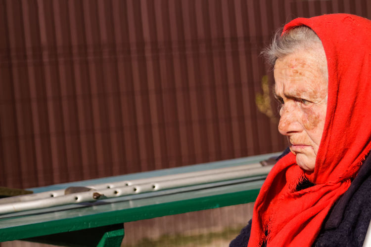 Ukrainian woman in red shawl outside. woman 85 years old. sick and homecare. dementia, memory
