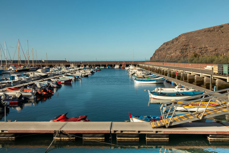 Boats moored at harbor against clear sky