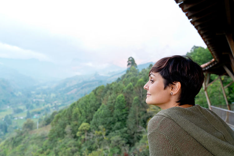 Side view of young woman standing against mountain